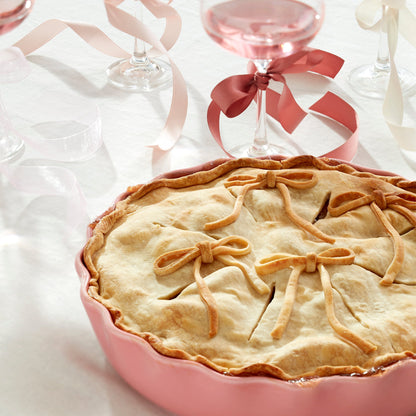 Pie with decorative crust in a pink dish on a white background