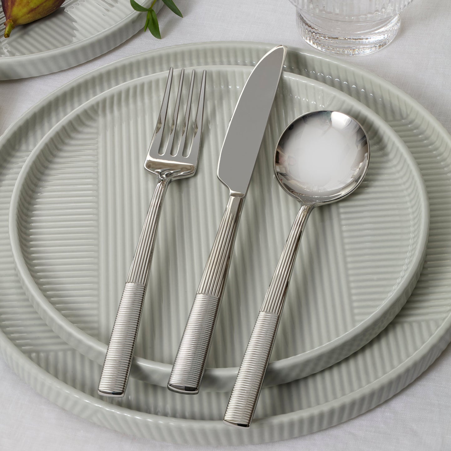 Silver cutlery set on a textured green plate with a light background