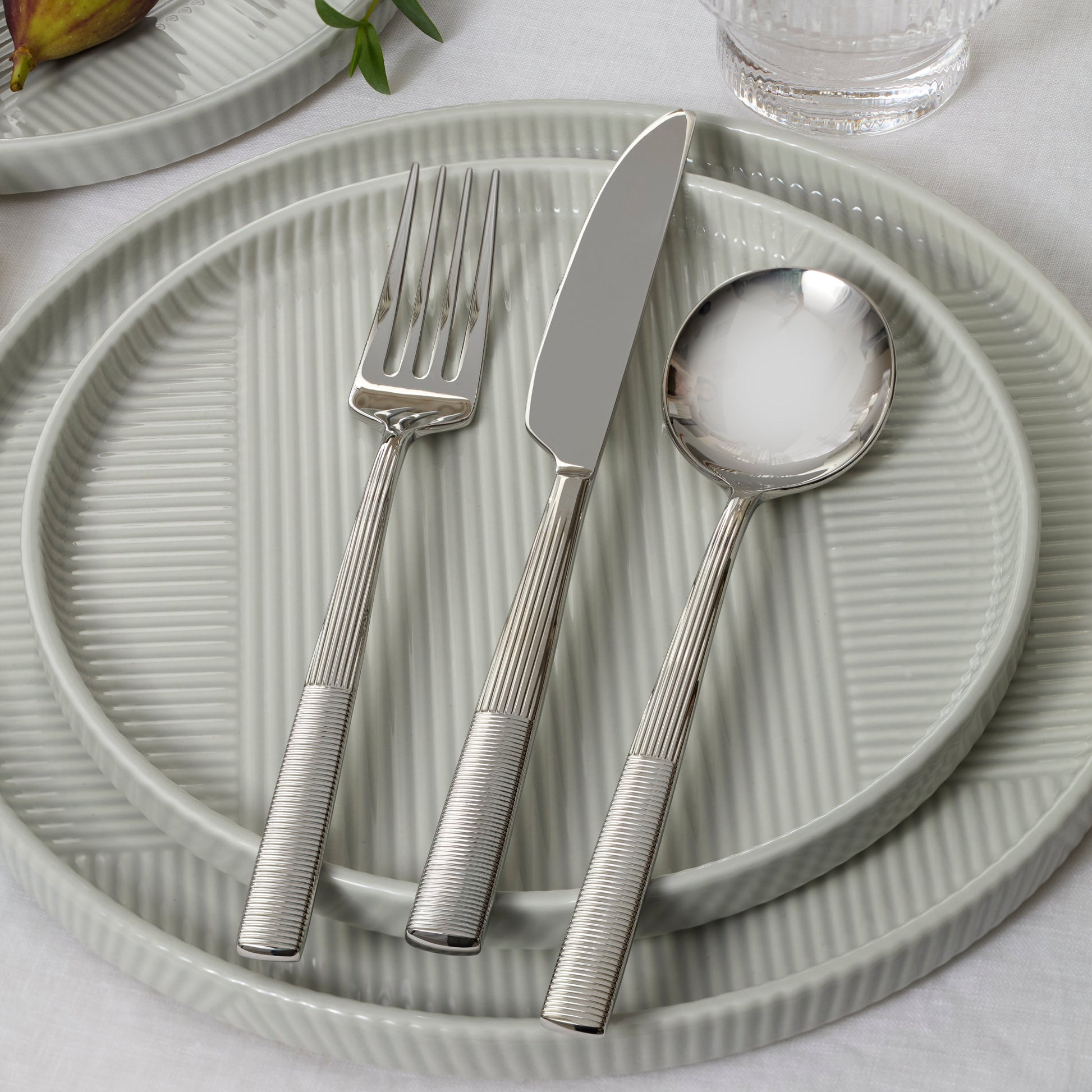 Silver cutlery set on a textured green plate with a light background