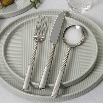 Silver cutlery set on a textured green plate with a light background